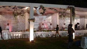 An outdoor event with a stage and tables, decorated with floral arrangements and draped fabric. - Hotel Jaipur Ashok (Jaipur)