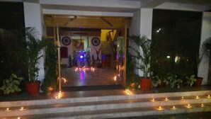 A hotel entrance with steps leading up to a door, decorated with string lights and potted plants. - Hotel Jaipur Ashok (Jaipur)