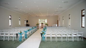 Interior de iglesia con bancas dispuestas en filas, un pasillo blanco y una alfombra verde.