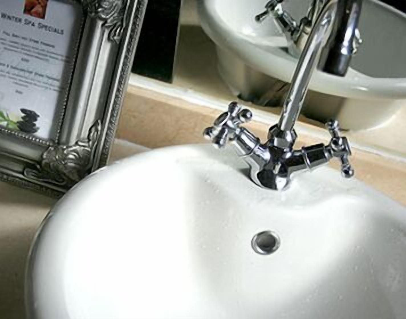 Ein Waschbecken mit einem Wasserhahn und einem gerahmten Bild, das an der Wand lehnt.