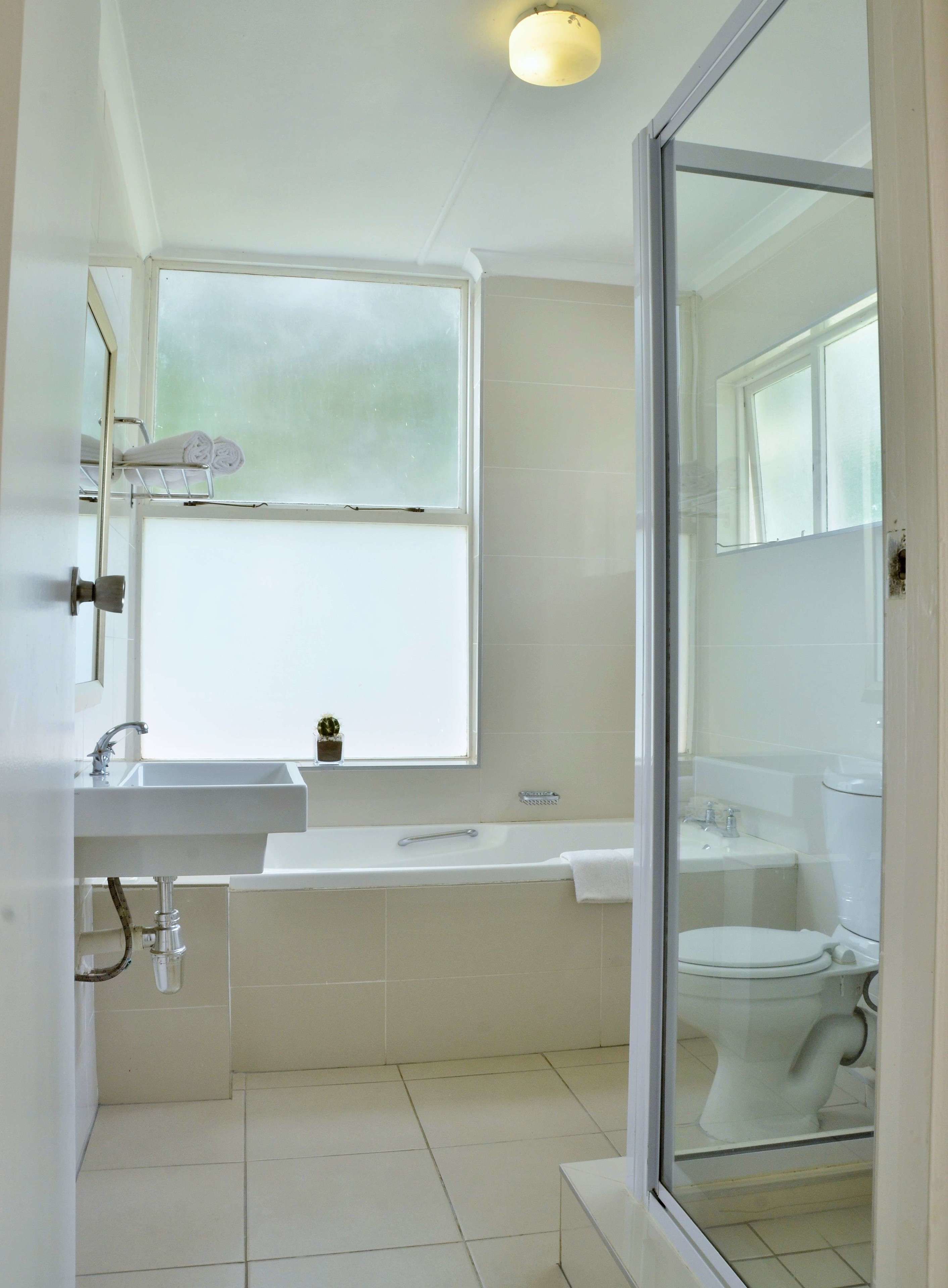 A bathroom with a window, a sink, a bathtub, and a toilet.