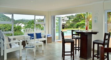 Una habitación amplia con ventanas grandes, vistas a la piscina y una zona de bar.