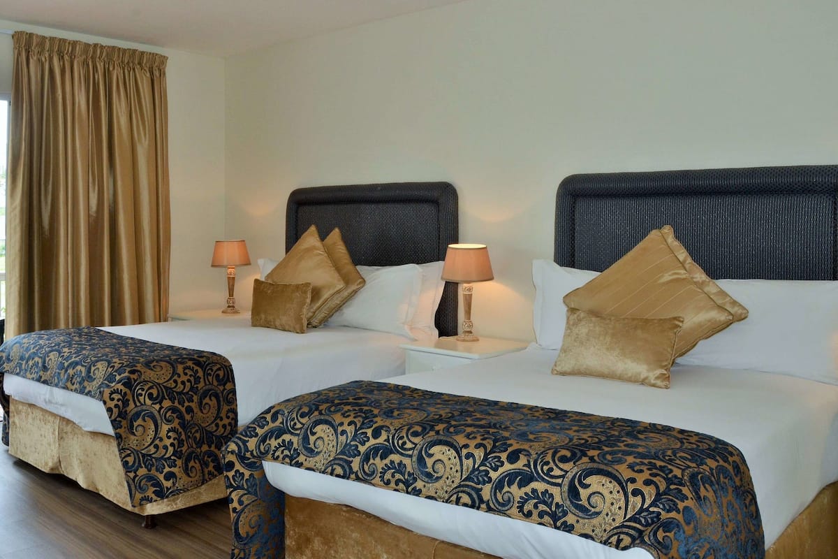 Ein Hotelzimmer mit zwei Betten, einem kleinen Tisch, Stühlen und Blick ins Freie.