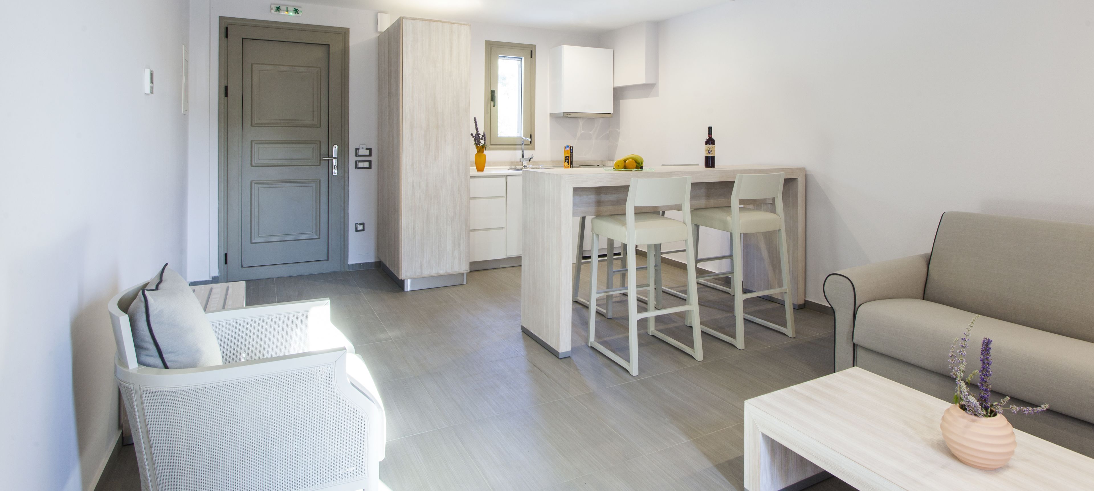 A modern, well-lit living area with a sofa, a dining table, and a kitchen area with a bar.