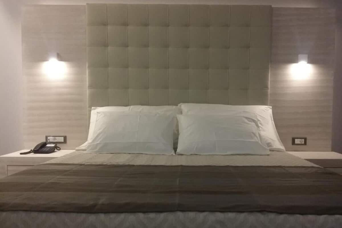 A neatly made bed with a tufted headboard, two bedside lamps, and a telephone on the nightstand.