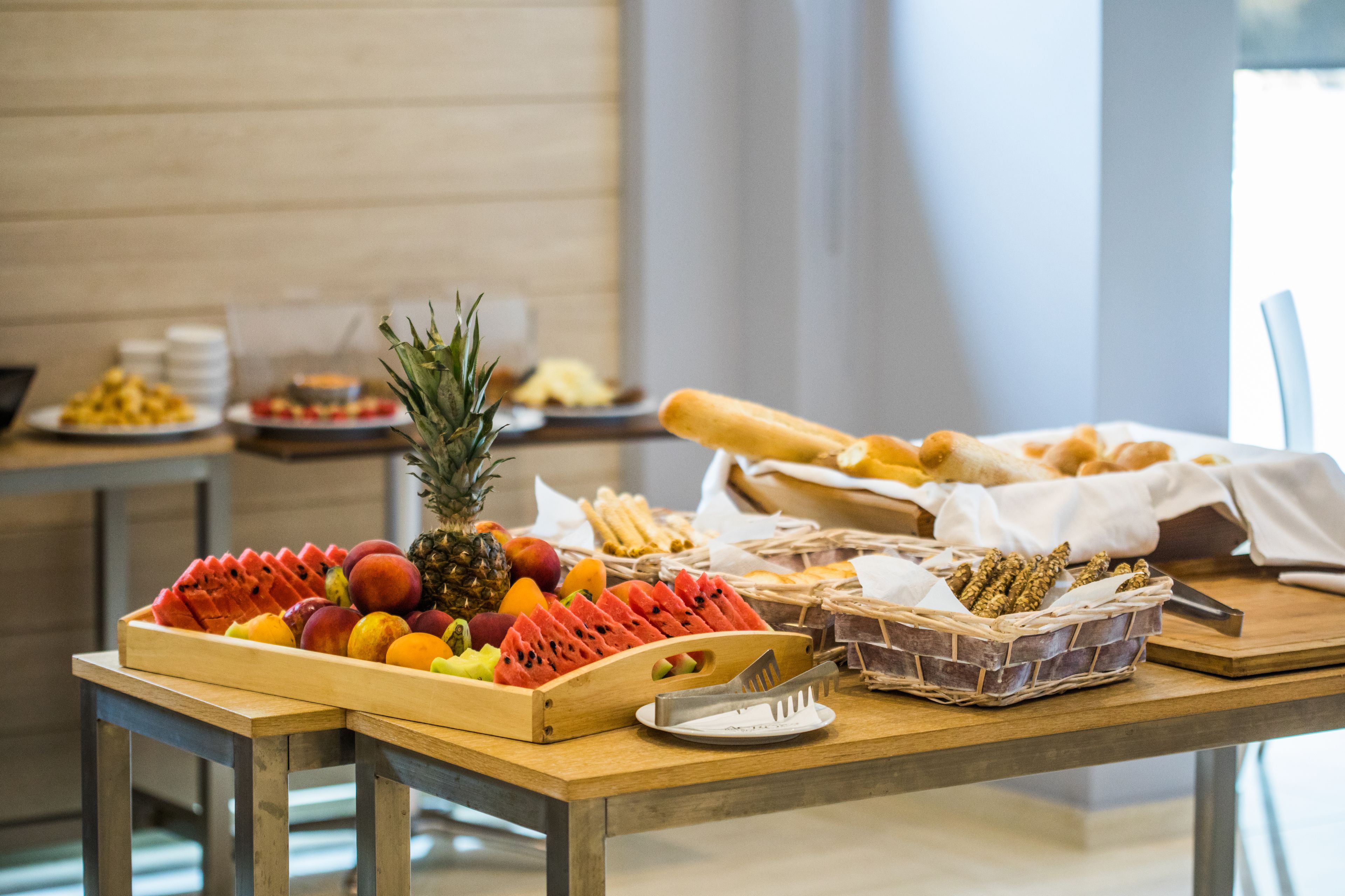A buffet table with various fruits, bread, and a pineapple.