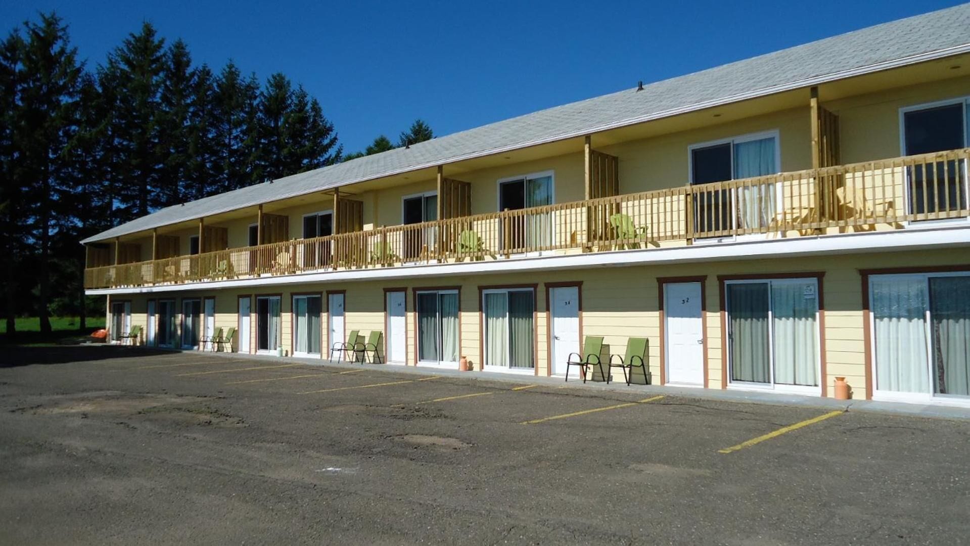 Un motel comprenant plusieurs chambres, un parking et un espace extérieur abrité.