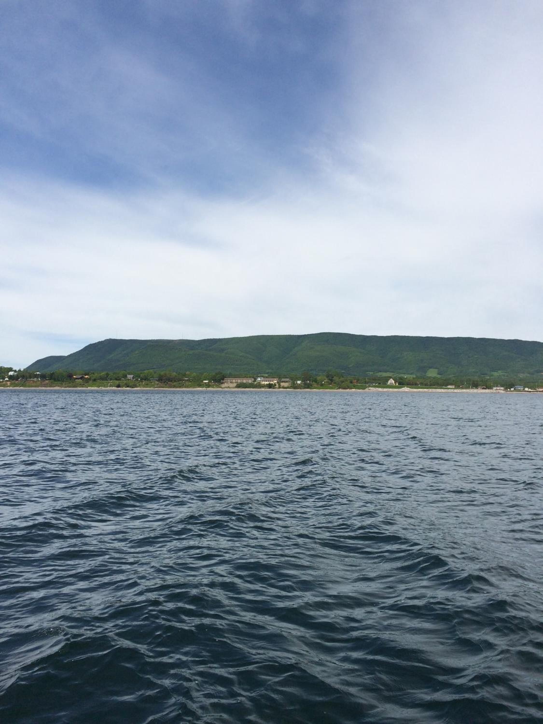 Une vue d’une zone côtière, avec une montagne en arrière-plan et une étendue d’eau au premier plan.