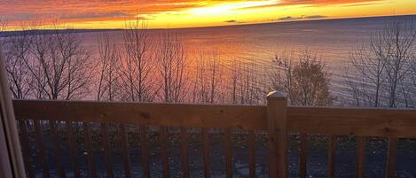 A wooden deck overlooking a body of water with a sunset.