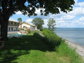 A lakeside hotel with outdoor seating and a view of the water. - Motel Carleton sur mer (Carleton-sur-Mer)