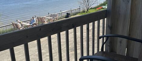 A balcony with a view of the water, wooden railings, and a chair.
