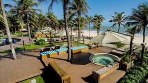 Un resort con zona de piscina, sillas de descanso y vistas a la playa.