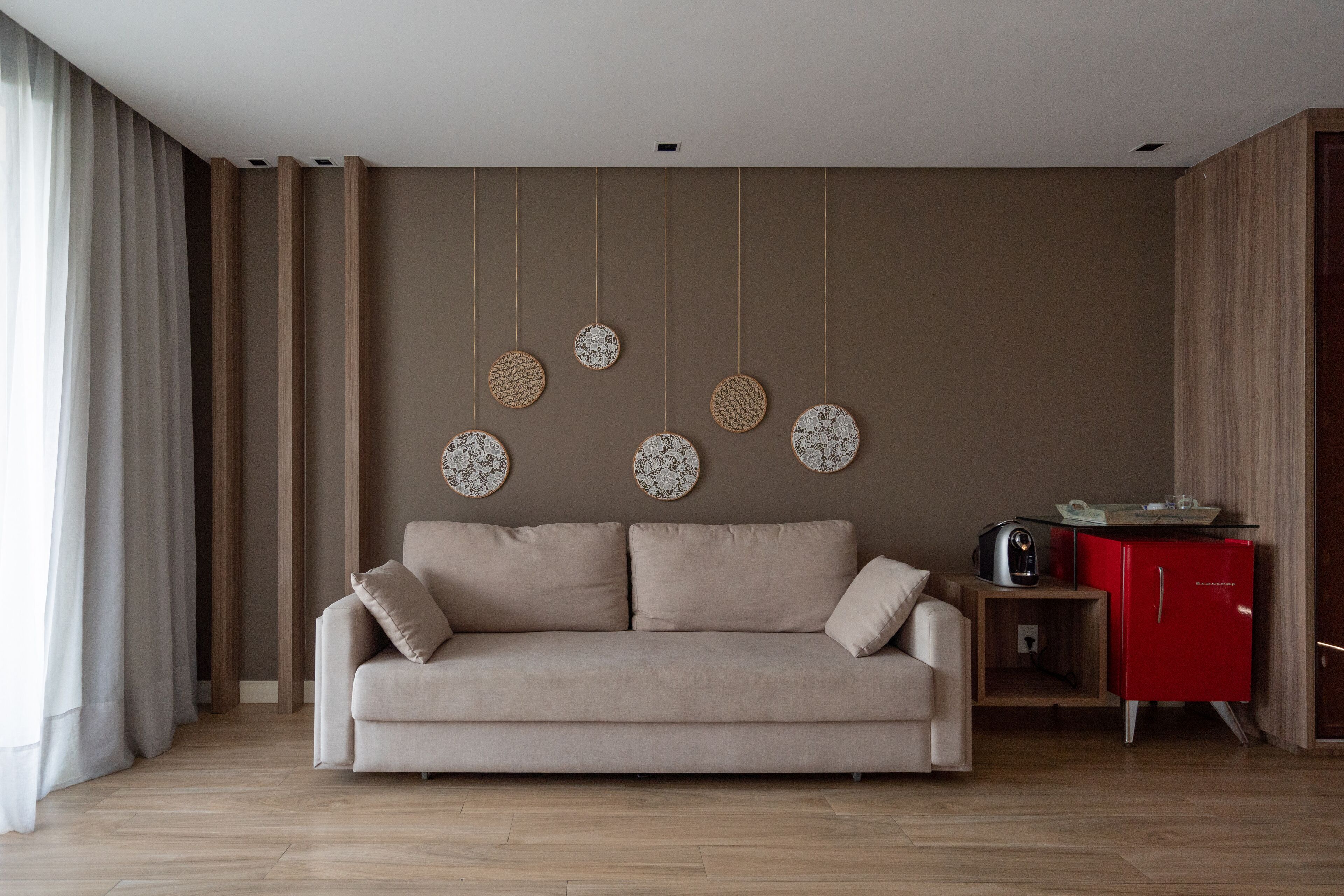 A modern living room with a beige sofa, a red cabinet, and wall-mounted circular decorations.