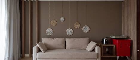 A modern living room with a beige sofa, a red cabinet, and wall-mounted circular decorations.