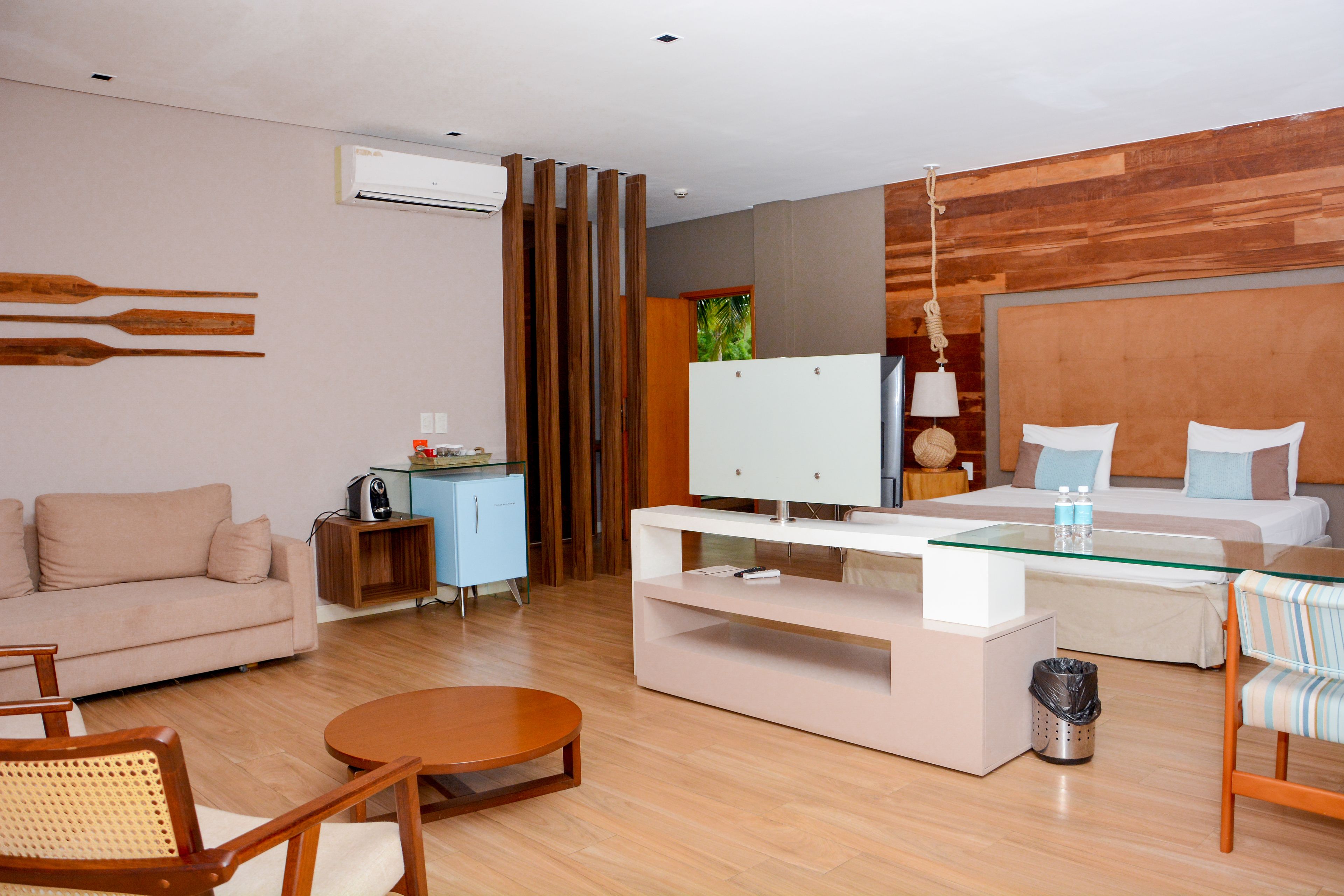 Una habitación de hotel moderna con sofá, una mesa de comedor, televisión y cama.