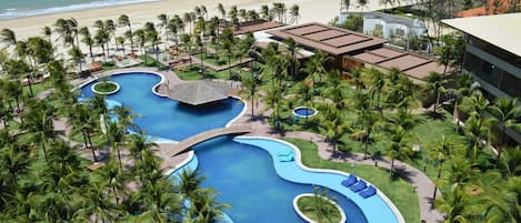 A resort with multiple swimming pools, palm trees, and a beach view.