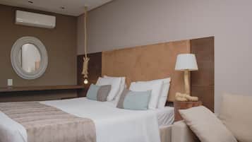 A hotel room with a large bed, a round mirror, a bedside lamp, and a wooden headboard.
