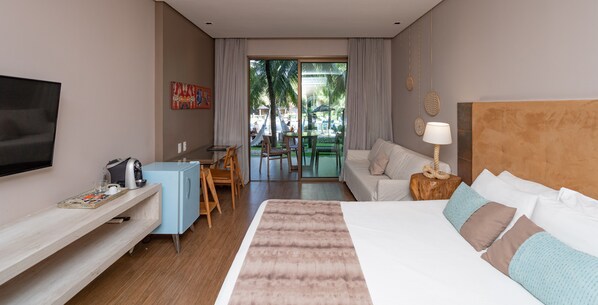A hotel room with a bed, a TV, a desk with a chair, a sofa, and a view of the outside.