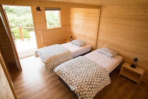 A wooden cabin room with two beds, a small table, and a window.