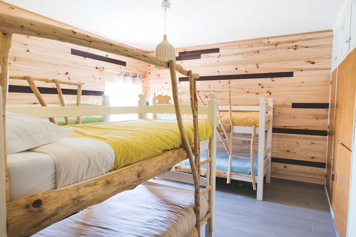 Une chambre avec un lit superposé, des murs en bois et un luminaire suspendu.