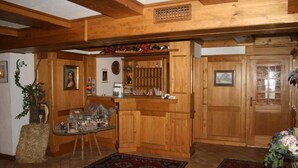 A wooden interior with a kitchen area, a dining table with chairs, and a large wooden door. - Gästehaus Wild (Oberasbach)