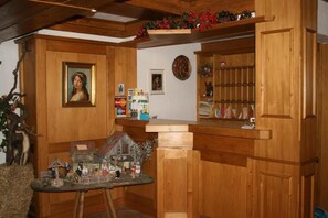 A wooden interior with a small table displaying figurines, a framed portrait, and a shelf with various items. - Gästehaus Wild (Oberasbach)