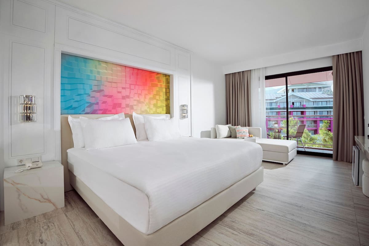 Une chambre d’hôtel moderne, dotée d’un grand lit, d’un canapé, d’un bureau et offrant une vue sur le paysage urbain.