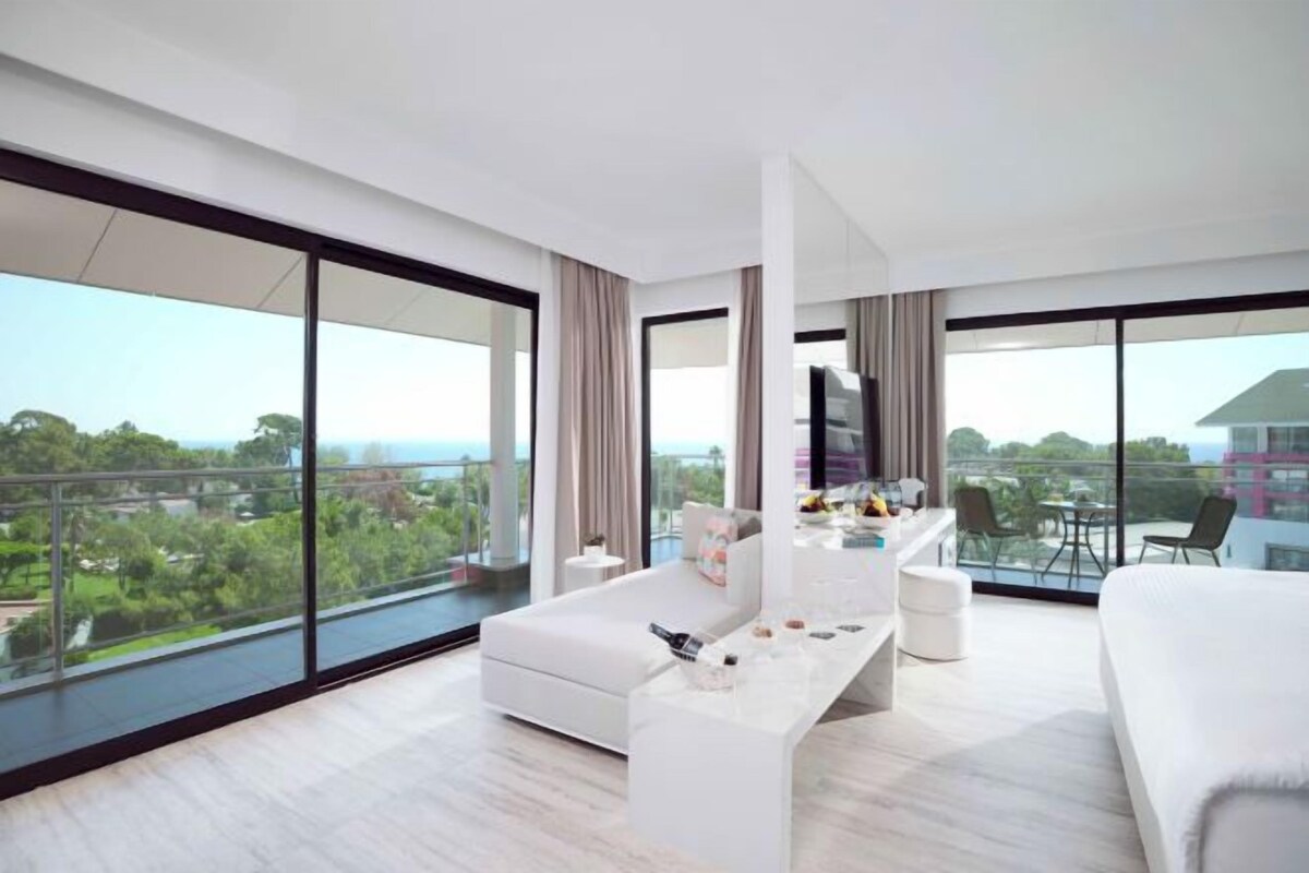 Une chambre d’hôtel moderne dotée d’un grand balcon, d’un canapé, d’une table basse et d’un téléviseur.