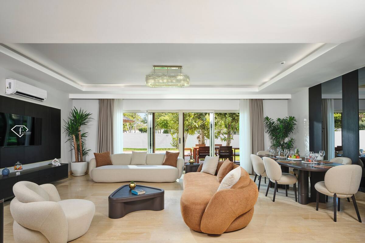 Un salon moderne comprenant un canapé, des fauteuils, une table basse, un téléviseur et un coin repas avec une table et des chaises.