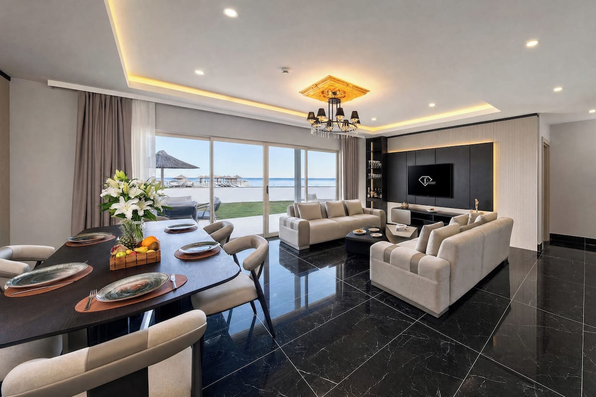 Un salon moderne avec un coin repas, un grand téléviseur et une vue sur la plage.