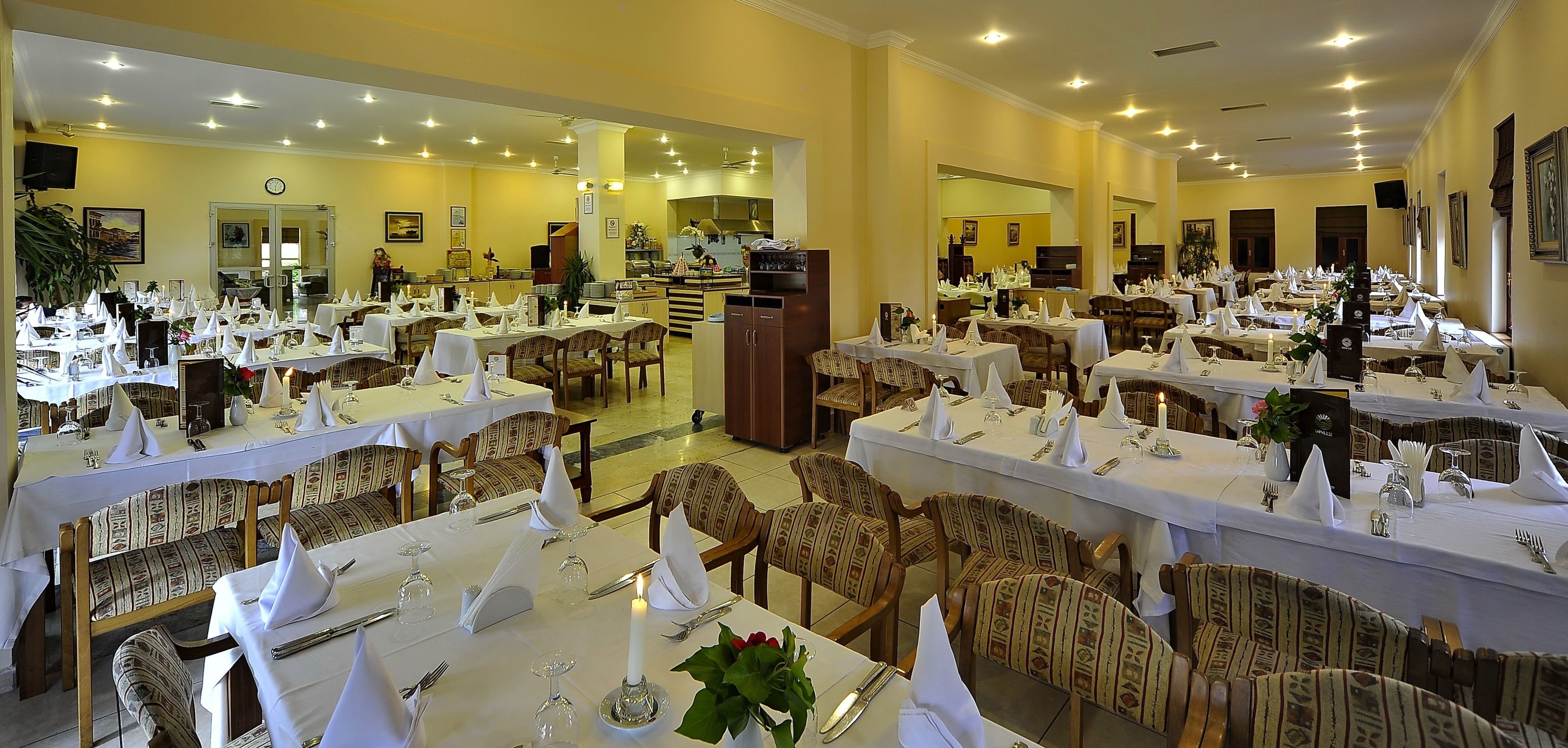 A restaurant with multiple dining tables set with white tablecloths, chairs, and candles.