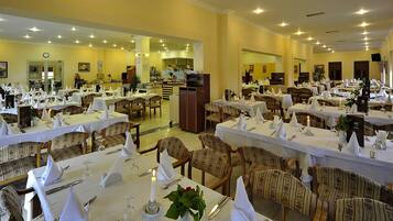 A restaurant with multiple dining tables set with white tablecloths, chairs, and candles.