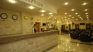 Una zona de recepción con pared de piedra, relojes y un cartel que dice "RECEPTION".