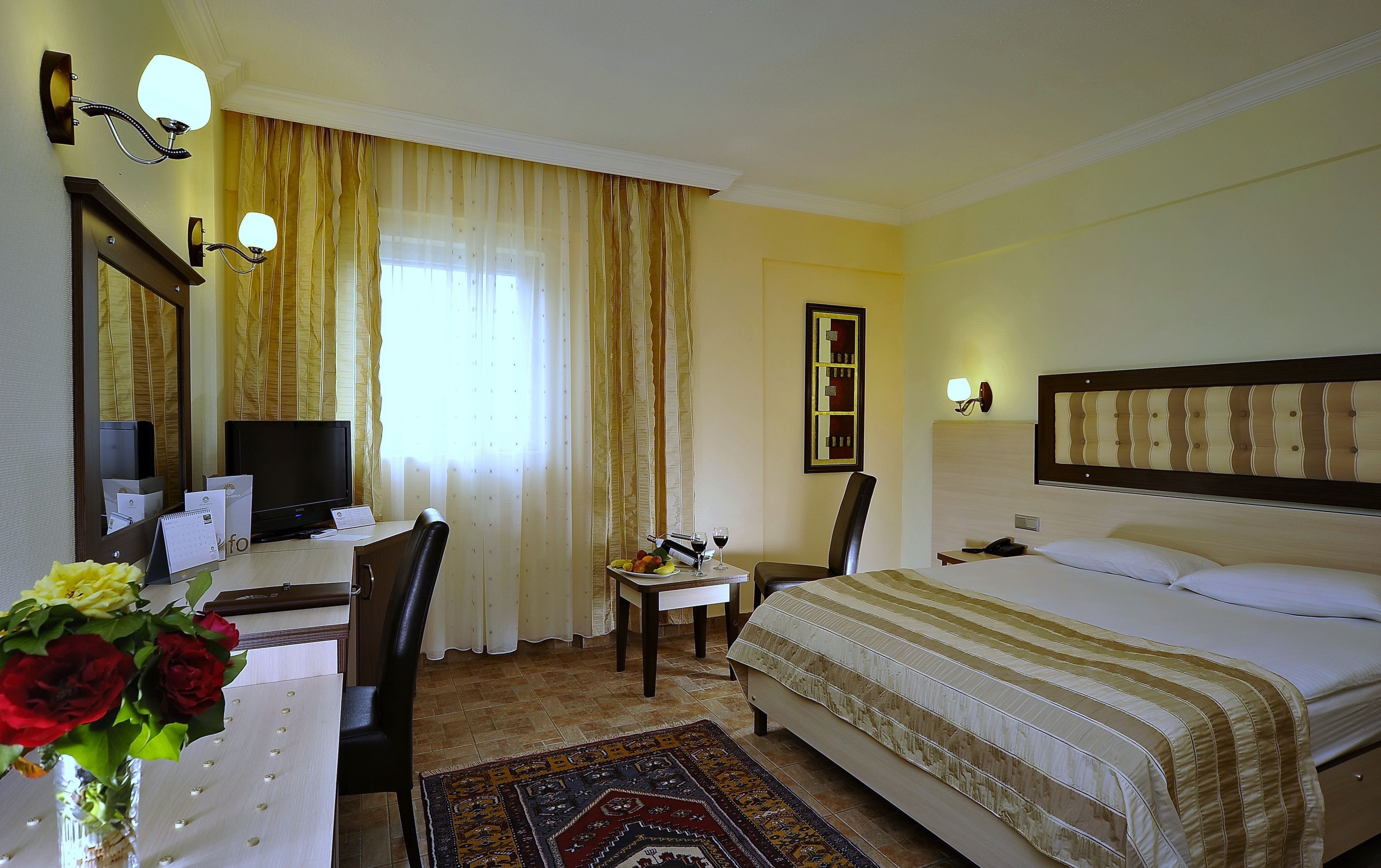 A hotel room with a bed, desk, chair, and a television.