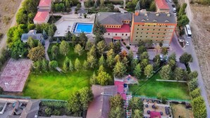 Vista aérea de un hotel con varias edificaciones, una piscina y abundante vegetación circundante.