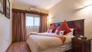 Une chambre d’hôtel avec un grand lit, un plancher en bois, une table de chevet et une fenêtre avec des rideaux.