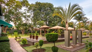 Un jardin aménagé avec des allées, des arbustes taillés avec soin et des palmiers.