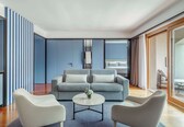 A modern living room with a striped sofa, two armchairs, a coffee table, and a large window.