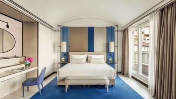 Ein Hotelzimmer mit einem großen Bett, einem Schreibtisch mit Stuhl, einem Spiegel und Blick ins Freie.