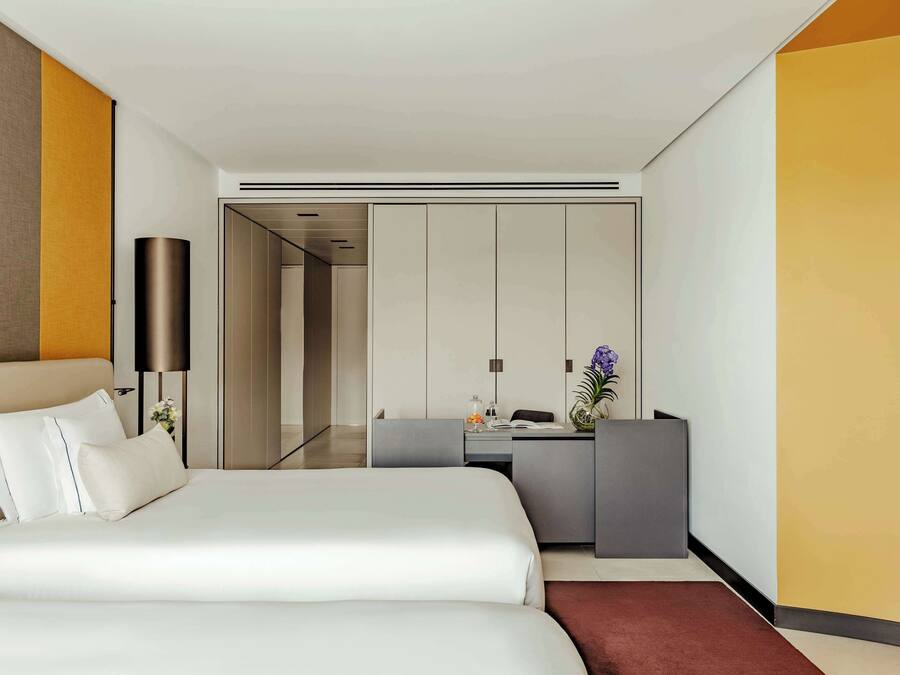 Quarto de hotel moderno com uma cama grande, uma escrivaninha e um guarda-roupa.