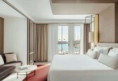 A hotel room with a bed, a sofa, a coffee table, and a view of the sea.