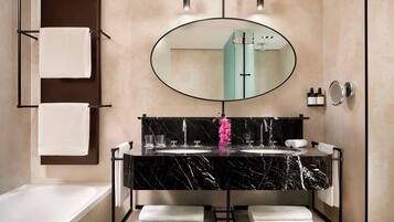 A modern bathroom with a black marble sink, a large mirror, and a towel rack.