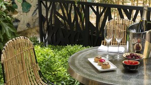 Een ronde tafel met een fles champagne, twee glaasjes, een bord met desserts en een schaal aardbeien.