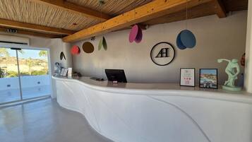 A reception desk with a modern design, featuring a wooden ceiling and a large window offering a view of the outdoors.