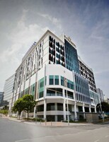 A modern hotel with a prominent glass facade, multiple floors, and a central entrance.
