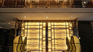 Un hall d’entrée luxueux, agrémenté d’un imposant lustre, d’un plafond haut et d’un espace salon avec des fauteuils modernes.