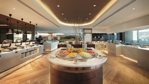 Un buffet de petit-déjeuner moderne, doté d’un îlot central, de plusieurs présentoirs de nourriture et d’un aménagement spacieux.