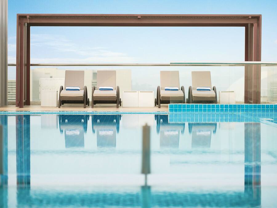 A pool area with lounge chairs and a glass balustrade.