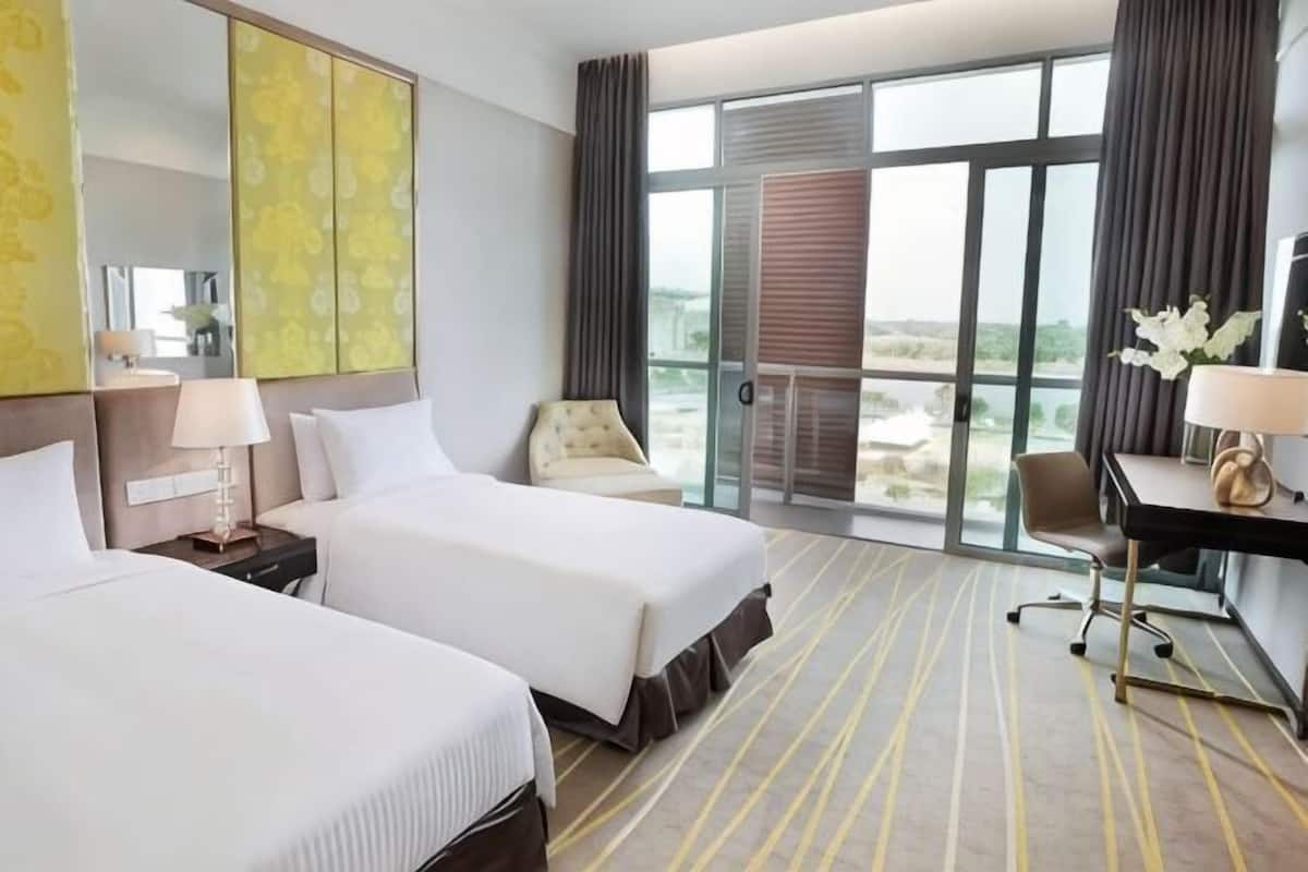 Een hotelkamer met twee bedden, een bureau, een stoel, een groot raam en een balkon.