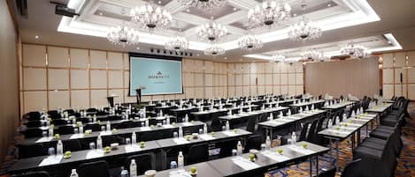Un salón de conferencias con filas de mesas, sillas y una pantalla de proyector que muestra 'DORSETT'.